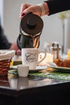 a person is pouring coffee into a cup on a table at B&B Montenakerhof in Riemst