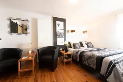 a bedroom with a bed and a chair and a mirror at B&B Montenakerhof in Riemst