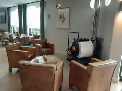 a waiting room with chairs and tables and a tv at Hotel Limburgia in Kanne
