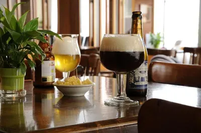 a table with two glasses of beer and a bottle at Hotel Limburgia in Kanne