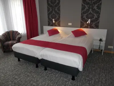 a large bed with red pillows in a hotel room at Hotel Limburgia in Kanne