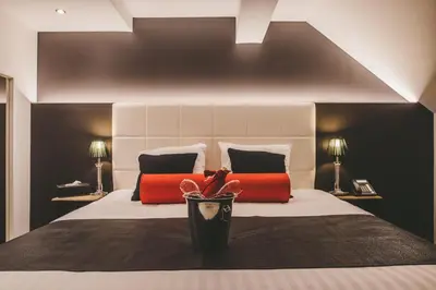 a bedroom with a bed with red and black pillows at Hôtel Hors-Château - Liège Centre Historique in Liège