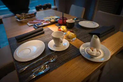 a wooden table with white plates and cups and spoons at Hôtel Hors-Château - Liège Centre Historique in Liège