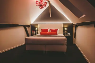 a bedroom with a bed with a red pillow at Hôtel Hors-Château - Liège Centre Historique in Liège