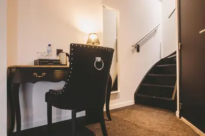 a room with a desk and a chair and a table and stairs at Hôtel Hors-Château - Liège Centre Historique in Liège