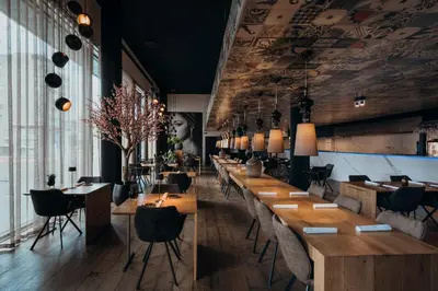 a restaurant with wooden tables and chairs and a wall of windows at Carbon Hotel in Genk