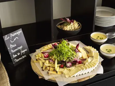 a plate of food with cheese and salad on a table at Park Inn by Radisson Liege Airport in Liège