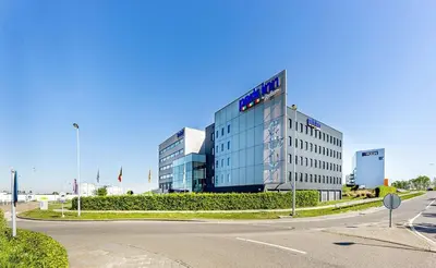 a large glass building with a sign in front of it at Park Inn by Radisson Liege Airport in Liège