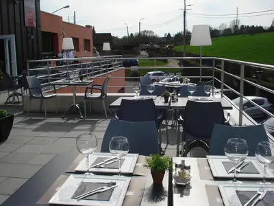 a restaurant with tables and chairs on a balcony at Hotel Le Midi in Petit-Rechain