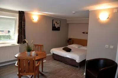 a hotel room with a bed and a desk and a table at Hotel Le Midi in Petit-Rechain