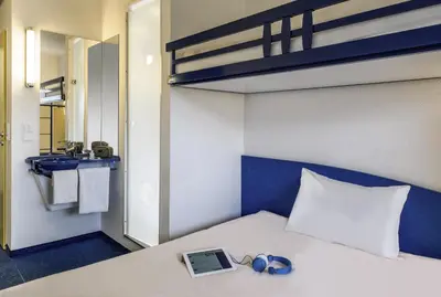 a bedroom with a bed with a laptop and a mirror at ibis budget Aachen Raeren Grenze in Raeren