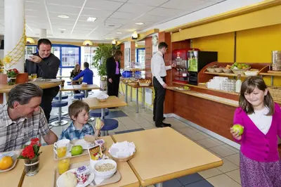 a man and two children eating food in a restaurant at ibis budget Aachen Raeren Grenze in Raeren