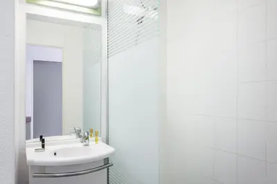 a white bathroom with a sink and a mirror at ibis budget Aachen Raeren Grenze in Raeren