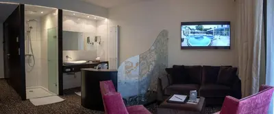 a hotel room with a bathroom with a tv on the wall at Le Chateau Des Thermes in Chaudfontaine