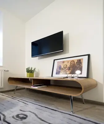 a living room with a desk with a tv on a wall at Xperience-Today Eupen in Eupen