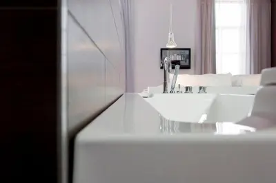 a white bathroom with a sink and a bed at Eburon Hotel in Tongeren