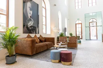 a living room with a couch and tables and windows at Eburon Hotel in Tongeren