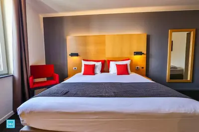 a bedroom with a large bed with red pillows at Hotel De La Couronne Liege in Liège