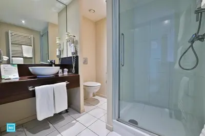 a bathroom with a glass shower and a sink at Hotel De La Couronne Liege in Liège