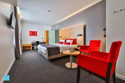 a hotel room with a bed and red chairs at Hotel De La Couronne Liege in Liège