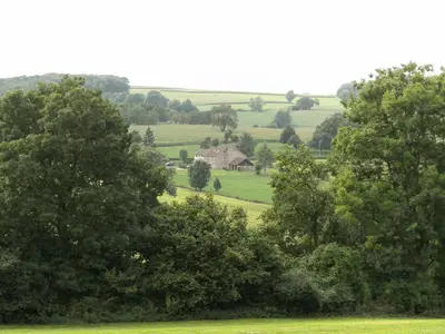 a house in the middle of a field with trees at 't Gulpdal Hotel Voeren-Teuven in Voeren