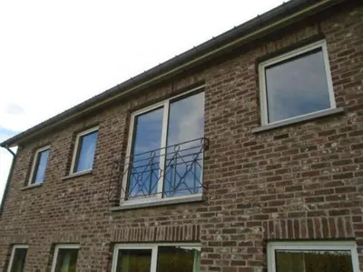 a brick building with a balcony on it at 't Gulpdal Hotel Voeren-Teuven in Voeren