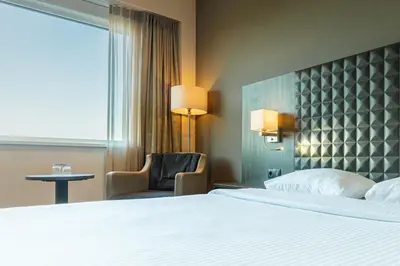 a hotel room with a bed and a chair and a window at Mezzo Hotel & Business in Beringen