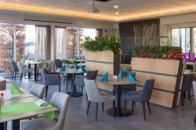 a restaurant with tables and chairs and plants at Mezzo Hotel & Business in Beringen