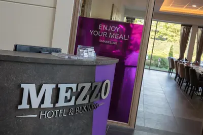 a sign in a room with a table and chairs at Mezzo Hotel & Business in Beringen