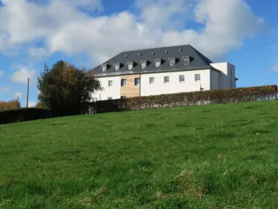 a white house on top of a grassy hill at Gîte Kaleo Eupen Jugendherberge in Eupen