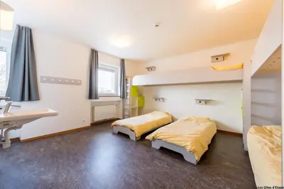 two beds in a room with a sink and a desk at Gîte Kaleo Eupen Jugendherberge in Eupen