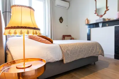a bedroom with a bed with a lamp on a table at De Koperen Geit in Kanne