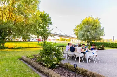 a group of people sitting at a table in a park at De Koperen Geit in Kanne
