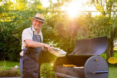 a man in a hat cooking on a grill at De Koperen Geit in Kanne