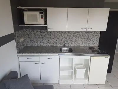 a white kitchen with a sink and a microwave at Studio Filo in Liège
