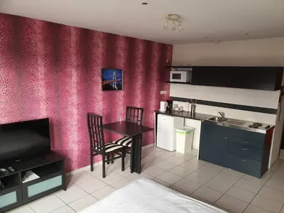 a kitchen with a table and chairs and a kitchen with pink walls at Studio Filo in Liège