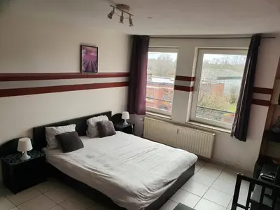 a bedroom with a bed and a large window at Studio Filo in Liège