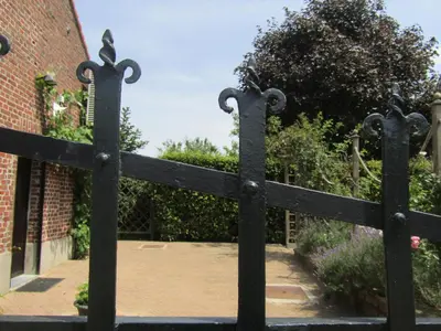 a black gate in front of a brick building at De Staberg in Bilzen
