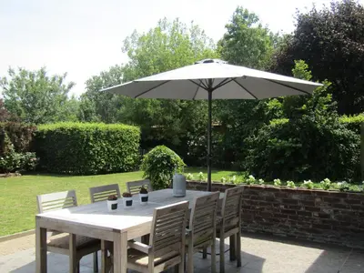 a table with an umbrella in a garden at De Staberg in Bilzen