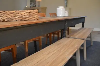 a row of wooden tables with a bench at De Staberg in Bilzen