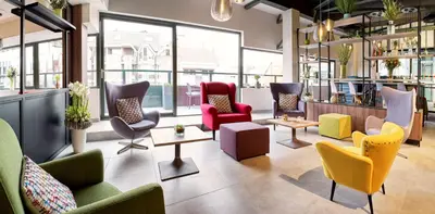 a lobby with colorful chairs and tables and windows at Park Inn By Radisson Hasselt in Hasselt