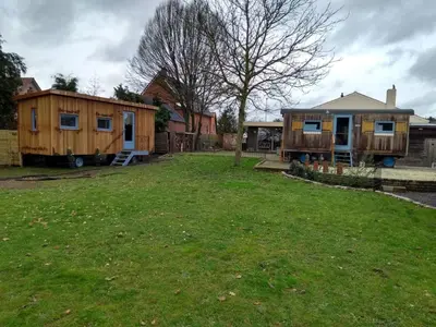 a yard with two tiny houses and a tree at B&B Dream On Wheels in Lommel