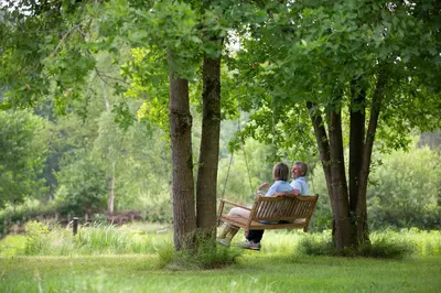 two women sitting on a park bench between trees at Vakantieverblijf Volmolen B&B in Maaseik