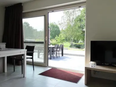 a living room with a sliding glass door with a table and chairs at Vakantieverblijf Volmolen B&B in Maaseik