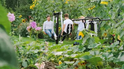 three people walking through a garden with sunflowers at De Pluktuin in Kortessem