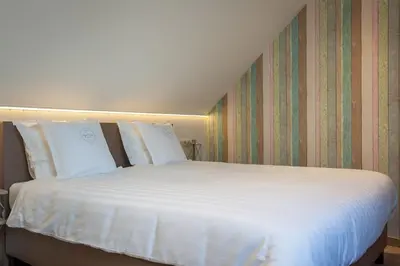 a large bed with white sheets and pillows at B&B Orgel Thuis in Kinrooi