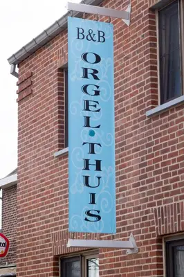 a large blue sign on the side of a brick building at B&B Orgel Thuis in Kinrooi
