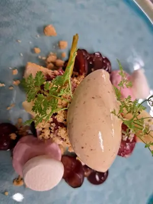 a plate with a dessert with grapes and a pear on it at La Ferme du Hélivy in Jalhay