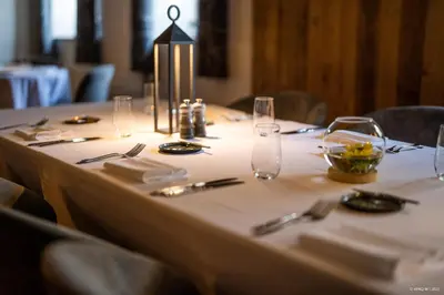 a table with a white table cloth with glasses and silverware at La Ferme du Hélivy in Jalhay