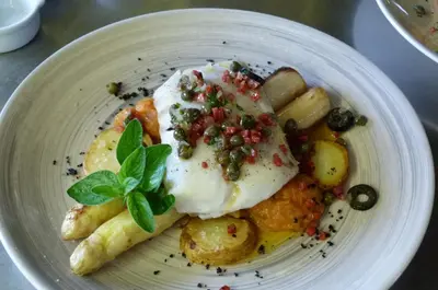 a white plate of food with eggs and fruit at La Ferme du Hélivy in Jalhay